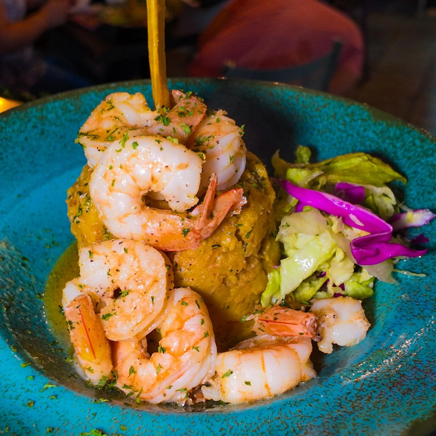 Mofongo con camarones y ensalada servido en un plato azul de Refranes